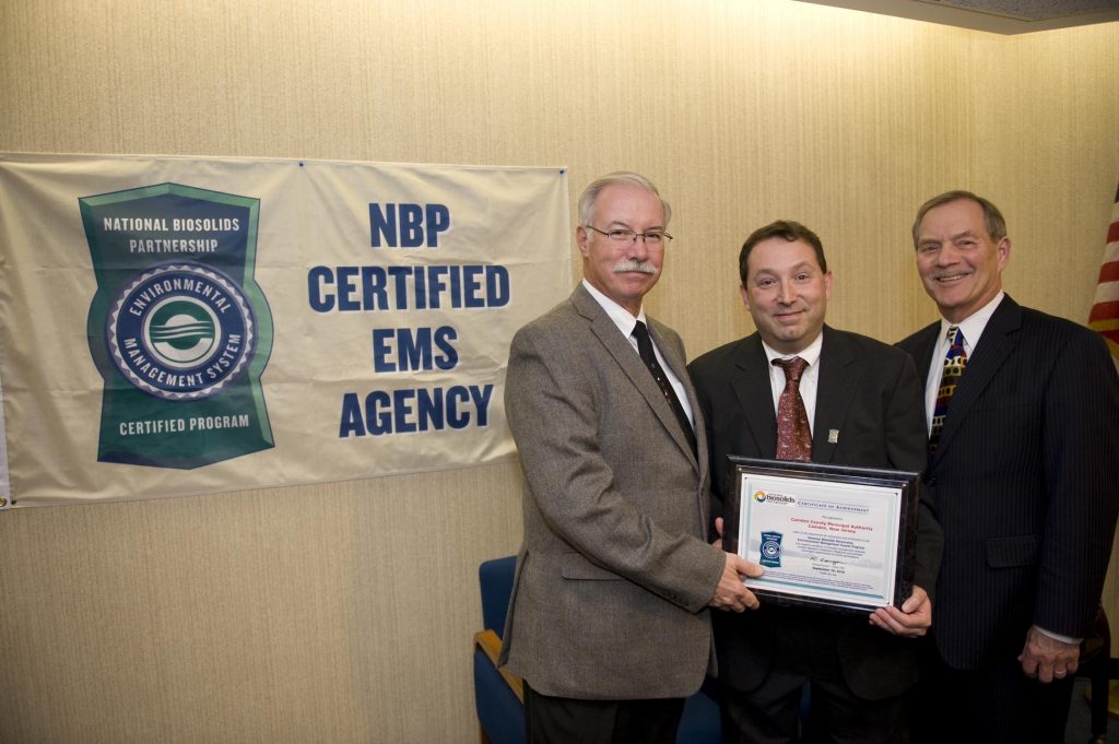 Three men in suits and ties holding a certificate.
